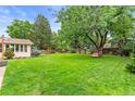 Expansive backyard featuring a large lawn, mature trees, and a tranquil seating area at 7442 S Wellington St, Centennial, CO 80122