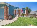 Inviting front entrance of this single-story home with blue painted accents, red brick, and a well-manicured lawn at 6085 S Parfet St, Littleton, CO 80127