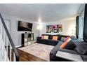 Inviting living room featuring hardwood floors, plush sectional sofa, media center, and staircase access at 4856 E Hinsdale Pl, Centennial, CO 80122