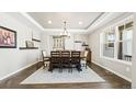 Dining room with tray ceiling, modern chandelier, hardwood floors, and large window at 8867 S Zante St, Aurora, CO 80016