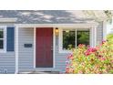 Charming home featuring a vibrant red door, complemented by gray siding and blooming flowers at 2260 Lilly Dr, Thornton, CO 80229