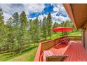 Inviting back deck area with a dining table set and relaxing lounge chairs surrounded by lush greenery at 28065 Camel Heights Cir, Evergreen, CO 80439