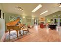 Spacious living room with a piano, stone fireplace, skylights, and large windows with natural light at 28065 Camel Heights Cir, Evergreen, CO 80439