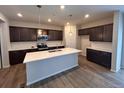 A spacious kitchen featuring dark cabinets, stainless steel appliances, and a large island with quartz countertops at 393 Grey Rock St, Brighton, CO 80601