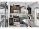 Compact kitchen features granite countertops, stainless steel appliances, and dark cabinets at 5131 Andes St, Denver, CO 80249