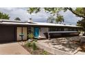 Contemporary single-story home features a blue front door, xeriscaping, and solar panels for energy efficiency at 3605 W Berry Ave, Littleton, CO 80123