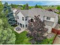 Spacious backyard featuring a stone patio with outdoor seating, mature trees, and lush lawn for entertaining and enjoying at 14878 E Aberdeen Ave, Centennial, CO 80016