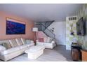 Bright living room with two sofas, a modern coffee table, and a staircase in the background at 2557 S Dover St # 85, Lakewood, CO 80227