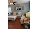 Bright living room with hardwood floors, comfortable white sofa, decorative pillows, and stylish ceiling fan and lamp at 15353 E 98Th Pl, Commerce City, CO 80022