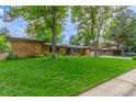 Brick home featuring a lush green lawn and mature trees and two car garage at 5890 W Quarles Dr, Littleton, CO 80128