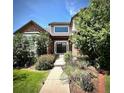 Inviting front entrance with brick facade, decorative door, lush landscaping, and charming walkway at 15857 E Aberdeen Ave, Centennial, CO 80016