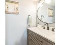 Bathroom featuring modern vanity with white countertop, black faucet, round mirror, and decorative artwork at 1470 S Quebec Way # 8, Denver, CO 80231