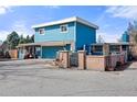 Bright blue two-story home featuring a garage, gated courtyard, and unique chimney design at 7400 W Quincy Ave, Littleton, CO 80123