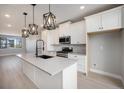 Open kitchen with modern pendant lighting, an island with sink, stainless appliances, and white cabinetry at 2078 S Holly St # 2, Denver, CO 80222