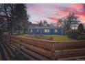 Charming blue home featuring a well-maintained lawn and rustic wood fence, ideal for suburban living at 7100 E 5Th Ave, Denver, CO 80220
