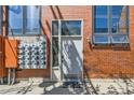 Exterior view of brick building with white front door, windows, and multiple electric meters at 2715 Blake St # 2, Denver, CO 80205