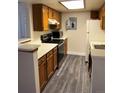 Functional kitchen featuring oak cabinets, updated appliances, and modern gray vinyl flooring at 931 S Zeno Way # 106, Aurora, CO 80017