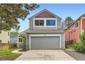 Two-story home with gray siding, a gray garage door, and a concrete driveway at 744 Owl Dr, Louisville, CO 80027