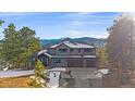 Attractive home with three-car garage, stone accents and a mountain view with snow at 4125 Aspen Ln, Evergreen, CO 80439