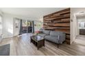 Bright living room with wood accent wall, light floors, and sliding glass door to a patio at 17493 E Mansfield Ave # 1231L, Aurora, CO 80013