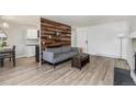 Inviting living room features wood accent wall, neutral paint, and light floors at 17493 E Mansfield Ave # 1231L, Aurora, CO 80013