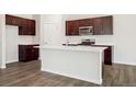 Modern kitchen with dark wood cabinets, stainless steel appliances, and a white center island at 2222 Flower Blossom Ave, Brighton, CO 80601