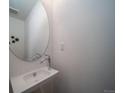 Modern powder room featuring a sleek, wall-mounted sink with a round mirror and contemporary fixtures at 13583 E 103Rd Ave, Commerce City, CO 80022