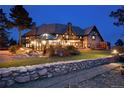 Expansive backyard featuring a glass conservatory, lush landscaping, and a stone retaining wall at 7225 Box Canyon Rd, Sedalia, CO 80135