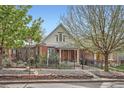 Charming brick home featuring a wrought iron fence and a mature shade tree in the front yard at 3356 Quivas St, Denver, CO 80211