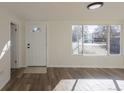 Bright living room with wood floors, large windows, and a white front door with a decorative window at 1435 Jay St, Lakewood, CO 80214