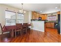 Dining room featuring beautiful hardwood floors, a large window with natural light, and an adjacent kitchen area at 4061 Nordland Trl, Castle Rock, CO 80109