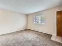 Cozy living room featuring neutral walls, carpet flooring, and a bright window at 8267 High St, Denver, CO 80229