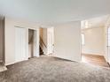 Open living room featuring neutral walls, plush carpet, with an open stairway and entry into another room at 8267 High St, Denver, CO 80229