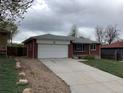 Charming brick home with a spacious driveway, attached garage, and well-maintained lawn at 1152 S Eaton St, Lakewood, CO 80232