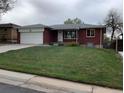 Charming brick home featuring an attached garage, well-manicured lawn, and a welcoming front entrance at 1152 S Eaton St, Lakewood, CO 80232