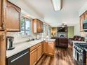 Cozy kitchen with wooden cabinets, modern appliances, and view to an adjacent living room with a fireplace at 11707 W 65Th Cir, Arvada, CO 80004