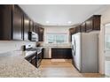 Modern kitchen features dark wood cabinetry, stainless steel appliances, and granite countertops at 56432 E 23Rd Ave, Strasburg, CO 80136