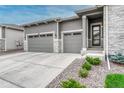Three car garage with gray doors, stone accents, modern exterior, and manicured landscaping at 1465 Gentle Rain Dr, Castle Rock, CO 80109