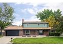 Charming two-story home with a brick facade, well-manicured lawn, and mature trees at 6982 Estes Dr, Arvada, CO 80004