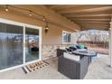 Relaxing covered patio with comfortable seating, a fire pit table, and outdoor lighting at 7604 S Lamar Ct, Littleton, CO 80128