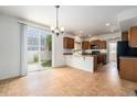 Open kitchen featuring tile floor, breakfast bar, wood cabinets, and sliding glass doors to backyard at 5572 Killarney St, Denver, CO 80249