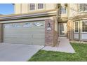 Attached two-car garage with brick accents and a manicured lawn at 10984 Alcott Dr, Denver, CO 80234