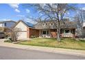 Inviting two-story home showcases a lush lawn, mature tree, and solar panels for energy efficiency at 10622 Van Gordon Way, Broomfield, CO 80021