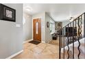 Bright foyer features tile flooring, decorative wood door, and staircase leading to the living area at 10622 Van Gordon Way, Broomfield, CO 80021