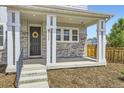 Welcoming front porch with stone accents, decorative wreath, and elegant white columns at 9111 W 100Th Way, Broomfield, CO 80021