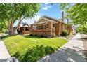 Inviting brick home featuring a lush green lawn and mature trees at 900 Jackson St, Denver, CO 80206