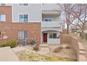 A condo with brick and gray siding, a red front door, and a small porch with stone landscaping at 5537 Lewis Ct # 1, Arvada, CO 80002