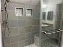 Modern bathroom shower features gray tile, built-in niche, and glass door at 2210 S Vaughn Way # 103, Aurora, CO 80014