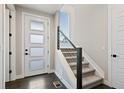 A modern staircase with carpeted steps, a window and a stylish, partially frosted door at 11350 W Grand Ave, Littleton, CO 80127