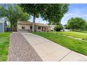 Single-story home with a well-manicured lawn and a long driveway at 3064 S Grape Way, Denver, CO 80222